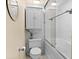 Bright bathroom featuring a toilet, tiled walls, decorative mirror and a glass enclosed tub with shower at 105 4Th Ne Ave # 219, St Petersburg, FL 33701