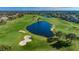 Aerial view showcases lush green golf course with a large water feature, sand traps, and surrounding residential homes at 10600 Indian Hills Ct, Seminole, FL 33777