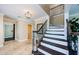 Inviting foyer with decorative lighting, tile flooring, and a staircase with ornate iron railings at 10600 Indian Hills Ct, Seminole, FL 33777