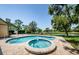 Inviting pool and spa area with lush landscaping and a tranquil view of the adjacent lake at 10600 Indian Hills Ct, Seminole, FL 33777