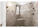 Walk-in shower featuring gray tiling, shower seat, rainfall shower head, and a strip of decorative mosaic tiles at 12536 116Th St, Largo, FL 33778