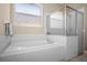 Bathroom featuring a soaking tub, glass-enclosed shower, decorative window, and tiled walls for a clean, spa-like feel at 1418 Hurley Pond Ln, Valrico, FL 33596