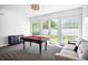 Bright game room features a billiard table, comfortable sofa, and a view of the outdoor scenery at 1418 Hurley Pond Ln, Valrico, FL 33596