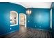 Stylish living room with rich blue walls, a statement chandelier, and natural light streaming through a window at 1418 Hurley Pond Ln, Valrico, FL 33596