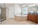 A relaxing bathroom featuring a soaking tub, vanity with dark countertop, and walk-in shower with glass door at 15930 Sorawater Dr, Lithia, FL 33547