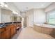 Large bathroom with dual vanities, a glass shower, a garden tub, and tile floors at 15930 Sorawater Dr, Lithia, FL 33547