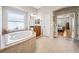 Well-lit bathroom showcases a garden tub with tiled surround, vanity, and an open doorway to the bedroom at 15930 Sorawater Dr, Lithia, FL 33547