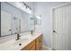 Bathroom featuring double sinks, a large mirror reflecting the shower and entry door at 15930 Sorawater Dr, Lithia, FL 33547