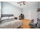 A serene bedroom with bamboo flooring, a bed, ceiling fan, a sofa, and a computer work space at 15930 Sorawater Dr, Lithia, FL 33547