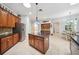 Well-lit kitchen with a center island, tile flooring, stainless steel refrigerator, and dark countertop at 15930 Sorawater Dr, Lithia, FL 33547