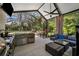 Wonderful patio with outdoor kitchen and wet bar, a ceiling fan, and comfortable seating area by the pool at 15930 Sorawater Dr, Lithia, FL 33547