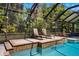 Enclosed pool area with lounge chairs, dining table, and lush greenery ensures privacy at 15930 Sorawater Dr, Lithia, FL 33547