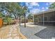 Backyard area showcasing a paver stone walkway, swing set, mature trees, and screened patio at 16608 Meadow Cove St, Tampa, FL 33624