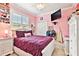 Bright bedroom with a white bed, purple comforter, and a built in book shelf at 16608 Meadow Cove St, Tampa, FL 33624