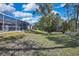 Expansive backyard featuring a screened-in pool enclosure, mature trees, and lush greenery at 17364 Mediterranean Cir, Weeki Wachee, FL 34614