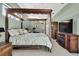 Large primary bedroom with dark wood canopy bed, ceiling fan, and TV with entertainment console at 17364 Mediterranean Cir, Weeki Wachee, FL 34614