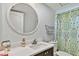A well-lit bathroom featuring a decorative shower curtain, modern sink, and a round mirror above the vanity at 2291 Americus W Blvd # 41, Clearwater, FL 33763