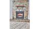 Close up of stone fireplace with logs burning, plus wood-look floors for cozy living space at 3045 Stratford Dr, Largo, FL 33771