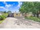 Single-story home with a long driveway, screened-in porch, and mature trees at 3214 W Rogers Ave, Tampa, FL 33611