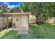 Exterior shot of the outbuilding with simple chair, neutral paint and concrete pad at 3214 W Rogers Ave, Tampa, FL 33611
