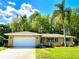 Charming single-story home features an attached garage, lush green lawn, and mature trees, with great curb appeal at 3240 Sand Key Dr, Palm Harbor, FL 34684