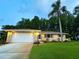Charming one-story home featuring an attached garage, well-maintained lawn, and mature landscaping including a majestic palm tree at 3240 Sand Key Dr, Palm Harbor, FL 34684