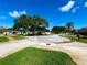 A quiet cul-de-sac street view featuring a large oak tree providing shade and a clear blue sky above at 3240 Sand Key Dr, Palm Harbor, FL 34684