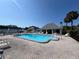 Wide view of community pool, pool house and lounge chairs with palm trees at 4237 Tamargo Dr # 4237, New Port Richey, FL 34652