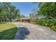 Quaint home with a brick facade and long driveway, surrounded by lush greenery and mature trees at 4315 W Azeele St, Tampa, FL 33609