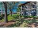 Condo featuring a screened lanai, balcony, lush landscaping, mature trees, and well-maintained lawn at 502 Hammock Pine Blvd # 502, Clearwater, FL 33761