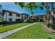 Condo building with red tile roof, mature trees, and well-manicured landscaping at 502 Hammock Pine Blvd # 502, Clearwater, FL 33761