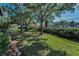 Well-maintained community grounds with mature trees, lush landscaping, and a tennis court in the background at 502 Hammock Pine Blvd # 502, Clearwater, FL 33761