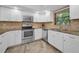 A well-lit kitchen features modern appliances, white cabinets, and stone backsplash at 502 Hammock Pine Blvd # 502, Clearwater, FL 33761