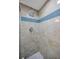 Updated shower features tiled walls with a blue glass tile accent stripe and rain style shower head at 502 Hammock Pine Blvd # 502, Clearwater, FL 33761