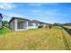 A spacious backyard shows the property's exterior, highlighting the covered patio and well-maintained lawn at 6398 Bradford Woods Drive, Zephyrhills, FL 33542