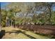 Spacious backyard featuring a well-maintained lawn and a tall brick wall bordered by trees at 717 Lighthouse Dr, Tarpon Springs, FL 34689