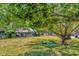The expansive backyard with mature trees and green grass, is visited by colorful peacocks at 8206 Leafy Ct, Port Richey, FL 34668