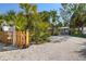 Welcoming gravel driveway entrance with palm trees, leading to a quaint home with a charming wooden fence at 8403 W Gulf Blvd, Treasure Island, FL 33706