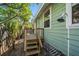 Exterior of home, featuring an outdoor shower with a wooden deck and steps leading to the side entrance at 8403 W Gulf Blvd, Treasure Island, FL 33706