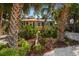 Charming home with tropical landscaping, featuring palm trees and a cozy seating area with an umbrella at 8403 W Gulf Blvd, Treasure Island, FL 33706