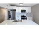 Close up of the modern kitchen featuring white cabinets, stainless steel appliances, and a quartz countertop island at 8719 Sunlit Cove Ne Dr, St Petersburg, FL 33702