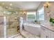 Bright bathroom with a freestanding tub, glass shower, and marble tiling throughout the space at 898 Cypress Lakeview Ct, Tarpon Springs, FL 34688