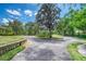 Circular driveway with manicured landscaping, mature trees, and a glimpse of the house on a sunny day at 898 Cypress Lakeview Ct, Tarpon Springs, FL 34688
