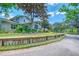 Charming home exterior featuring well-maintained landscaping, a wooden fence, and a paved driveway under a clear sky at 898 Cypress Lakeview Ct, Tarpon Springs, FL 34688
