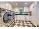 Bright laundry room with stainless steel washer/dryer, black countertops, and checkerboard tile floors at 898 Cypress Lakeview Ct, Tarpon Springs, FL 34688