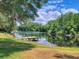 Scenic waterfront view featuring a private dock, lush trees, and lake at 898 Cypress Lakeview Ct, Tarpon Springs, FL 34688