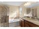 Bathroom featuring double sinks with granite countertops, a garden tub, and tiled walk-in shower at 9908 Spice Bush Ct, Tampa, FL 33647