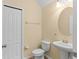 Cozy half bathroom featuring a pedestal sink and a classic round mirror and a two-panel door at 9908 Spice Bush Ct, Tampa, FL 33647