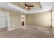 Comfortable carpeted bedroom boasting a tray ceiling, fan, and access to a walk-in closet at 9908 Spice Bush Ct, Tampa, FL 33647