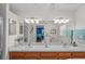 Well-lit bathroom with double sinks, wooden cabinets, and a large mirror at 11250 Hollander Ave, Hudson, FL 34667